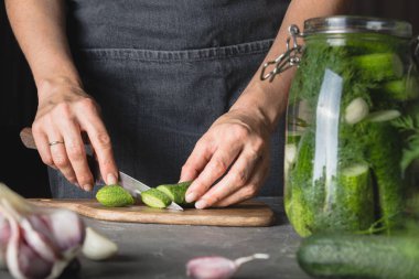 Kadın sarımsak ve dereotu ile salatalık pişirme. Rustik karanlık tarzı. Yakın çekim.