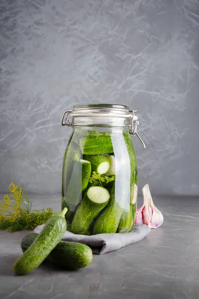Okurka a fermentační okurky ve skleněné nádobě s dillem a česnekem na tmavě šedé — Stock fotografie