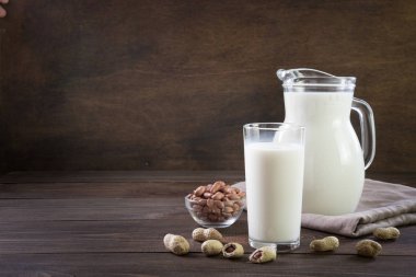 Cam ve koyu ahşap masada sürahi taze fıstık sütü. Rustik tarzı.