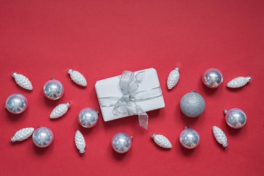 Kırmızı yüzeyde beyaz kağıt ve topları sarılmış Noel hediye kutusu. Yaratıcı düz yatıyordu, üst görünümü. Xmas.