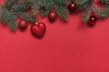 Kırmızı toplar ve kalp, kırmızı dökmeyen dalları Noel sınırı. Yukarıdan bakın, düz yatıyordu. Xmas tatili. Şablon, mockup, tebrik Yeni Yıl kartı.
