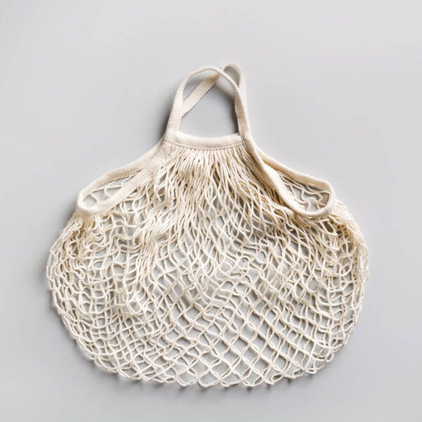 Empty eco shopping mesh bag on grey. Zero waste concept.