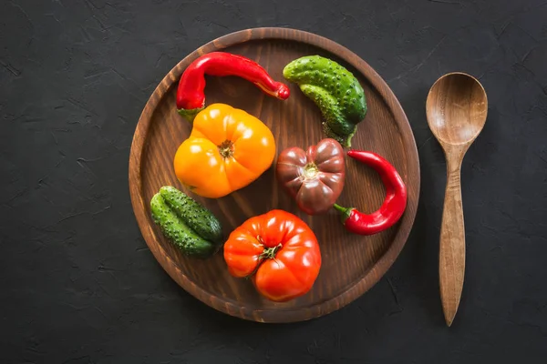 Feo tomate colorido orgánico, pimienta, pepino en bandeja de madera en hormigón negro. Concepto verduras ecológicas . —  Fotos de Stock