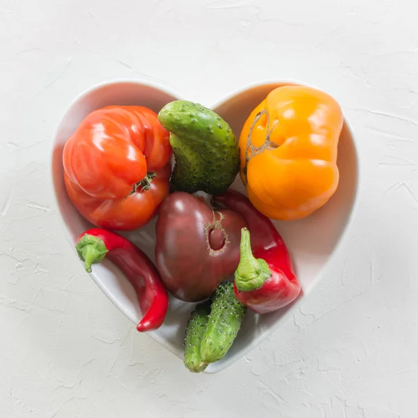 Feo tomate colorido orgánico, pimienta, pepino en el plato como corazón. Concepto verduras ecológicas . —  Fotos de Stock