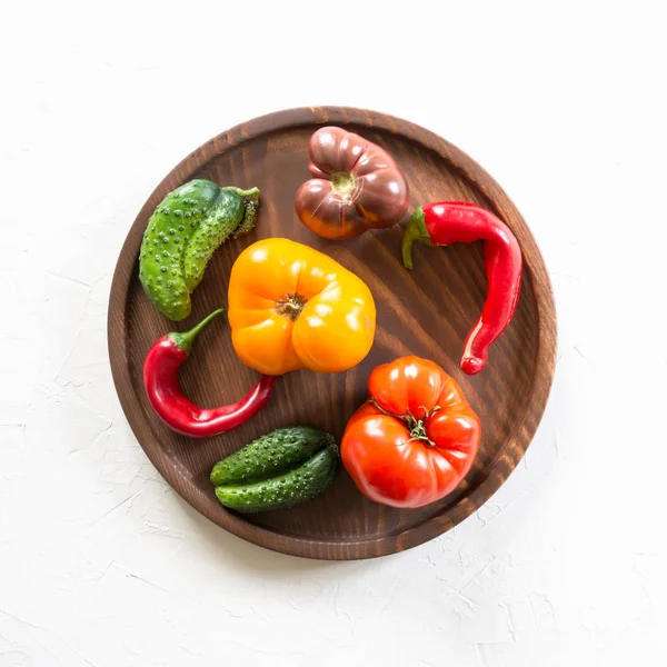 Feo tomate colorido orgánico, pimienta, pepino en plato de madera. Concepto verduras ecológicas . —  Fotos de Stock