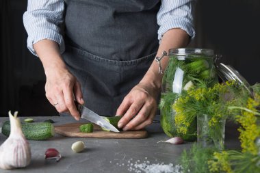 Kadın sarımsak ve dereotu ile turşu için salatalık kesme. Yakından kapatın. Yakın çekim.