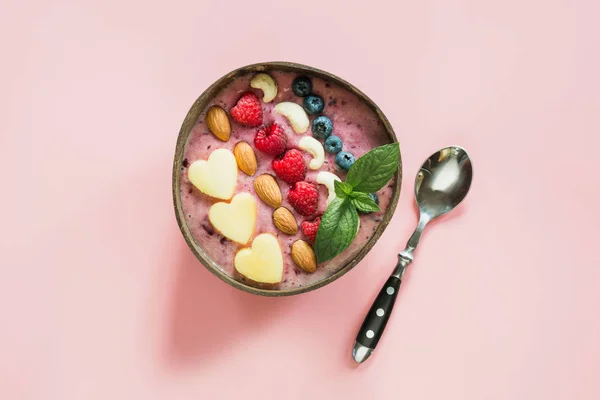 Desayuno saludable de plátano y batido de arándanos decorado con frutas en un bol de coco de color rosa . — Foto de Stock