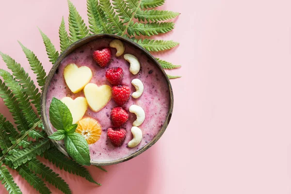 Desayuno saludable de plátano y batido de arándanos decorado con frutas en un bol de coco de color rosa . — Foto de Stock