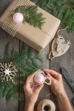 Noel tatili. Hediye kutusu, dekor, ip, köknar ağacı, dallar. Kadın bir hediye hazırlamak.