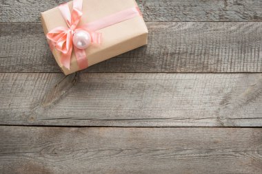 Ahşap tahta üzerinde ambalaj kağıdı ve pembe yay ve kurdele el yapımı hediye. Üst görünüm ve copyspace. Düz yatıyordu.