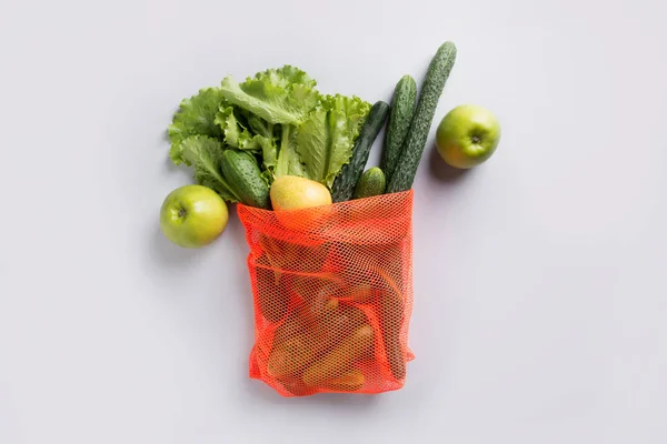 Zero waste. Orange shopping mesh bag with green vegetables. View from above.