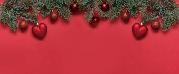 Weihnachtsrand aus roten Kugeln und Herz, immergrüne Zweige auf rot. Blick von oben, flach gelegen. Weihnachten. Vorlage, Grußkarte zum neuen Jahr. — Stockfoto