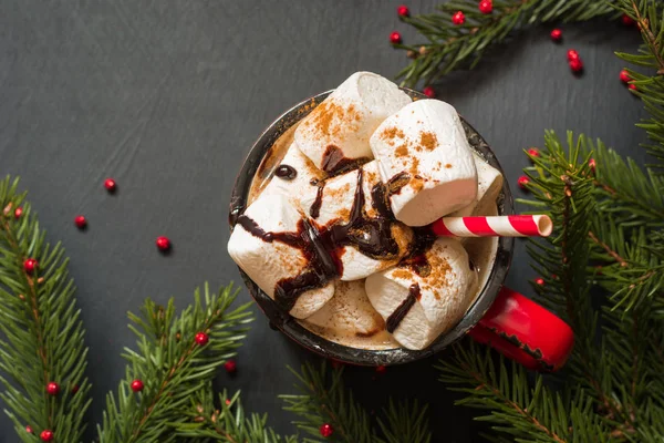 Becher mit heißer Schokolade und Kaffee mit Marshmallows mit Weihnachtsbaumzweigen auf schwarzem Hintergrund. Ansicht von oben. — Stockfoto