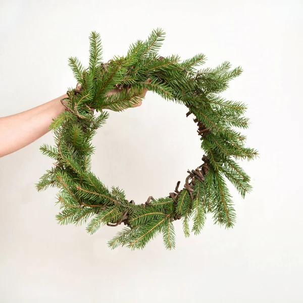 Corona natural fresca de Navidad de la rama de abeto en manos femeninas, sobre fondo blanco . — Foto de Stock