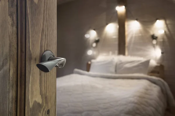 Opened door to blurred bedroom with farm wooden house interior as background.