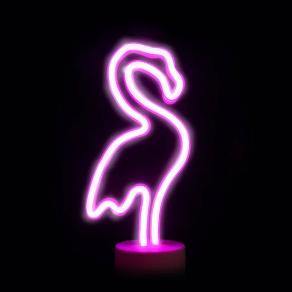 Neon pink flamingo LED lamp isolated on black.