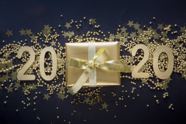 Siyah arka plan üzerinde altın kurdele ile lüks altın hediye kutusu. Noel hediyesi. Düz yatıyordu. Üst te. Şenlikli bir fon. Xmas deseni.