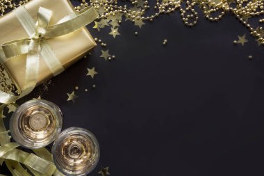 Parlak siyah arka plan üzerinde iki cam şampanya ile Lüks altın hediye kutusu. Noel partisi. Düz yatıyordu. Yukarıdan görüntüleyin. Xmas.