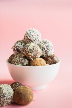 Ev yapımı enerji topları, kakao ile vegan çikolata truffle, pembe arka plan üzerinde hindistan cevizi. Çocuklar için sağlıklı gıda, tatlılar yerine.