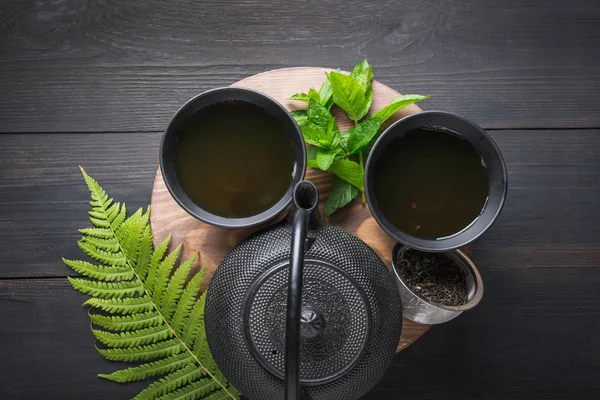 茶道。两杯茶，薄荷和水壶在黑暗的背景。中国茶的概念。从上面查看. — 图库照片