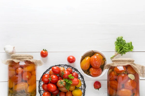 Консервовані овочі помідор у скляних банках на дерев'яній дошці. Вид зверху . — стокове фото