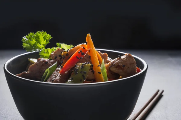 Udon fideos salteados con plato de cerdo y palillos sobre fondo de piedra negra. Cocina asiática . —  Fotos de Stock