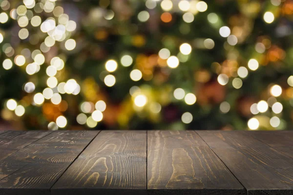 Koyu ahşap masa ve bulanık Noel ağacı bokeh. Xmas arka plan için ürün görüntüleme.