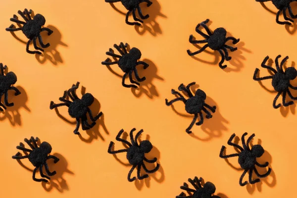 Schwarze Spinnen auf orange. Blick von oben. Offene Komposition. Muster der Halloween-Party. — Stockfoto