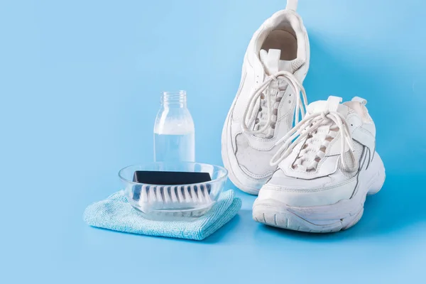 Zapatillas blancas sucias con herramienta especial para limpiarlas en azul . — Foto de Stock