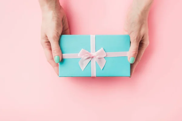 Caixa de presente azul na mão feminina em rosa pastel . — Fotografia de Stock