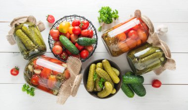 Tahta üzerinde cam kavanozlarda mayalanmış domates ve salatalık. Yukarıdan görüntüle.