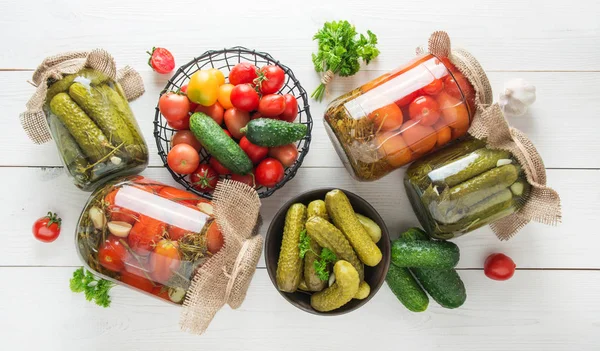 Tahta üzerinde cam kavanozlarda mayalanmış domates ve salatalık. Yukarıdan görüntüle.