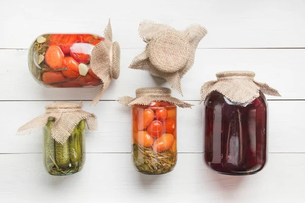 Konserve sebze salatalık ve domates cam kavanoz ahşap tahta üzerinde. Yukarıdan görüntüleyin. Ev yapımı hasat sonbahar hazırlıkları. Ödevler ve gelenekler.