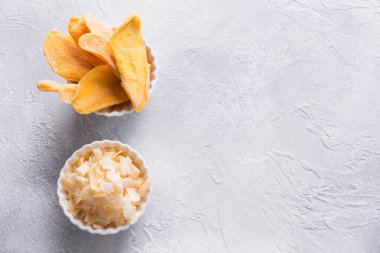 Susuz kalmış ve kurutulmuş mango ve hindistan cevizi cipsleri beyaz kasede. Kapat..