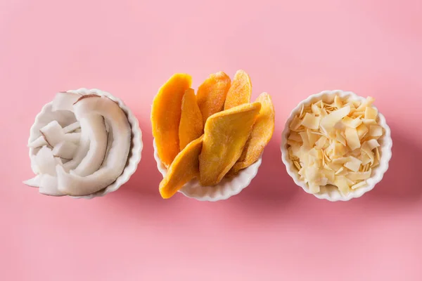 Dehydrierte und getrocknete Mango-Kokos-Chips in weißer Schüssel auf rosa. Nahaufnahme. — Stockfoto