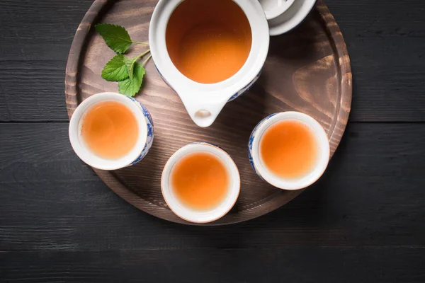 Teaszertartás. Három csésze tea melissával és teáskanna sötét háttérrel. Kínai tea koncepció. Kilátás felülről. — Stock Fotó