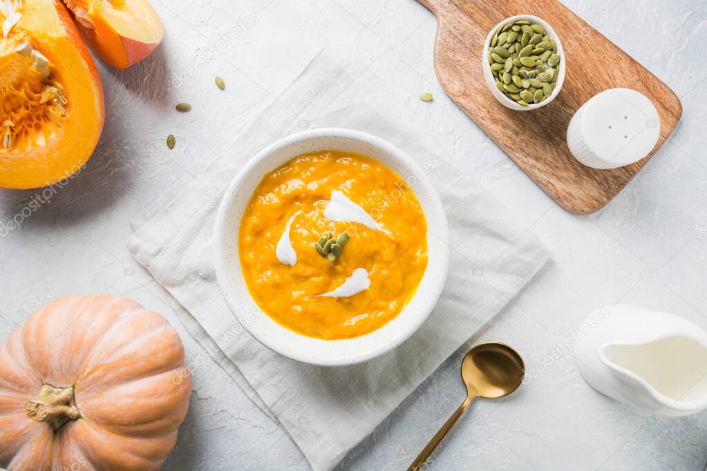 Pumpkin soup with cream on grey stone background. Copy space. Top view.