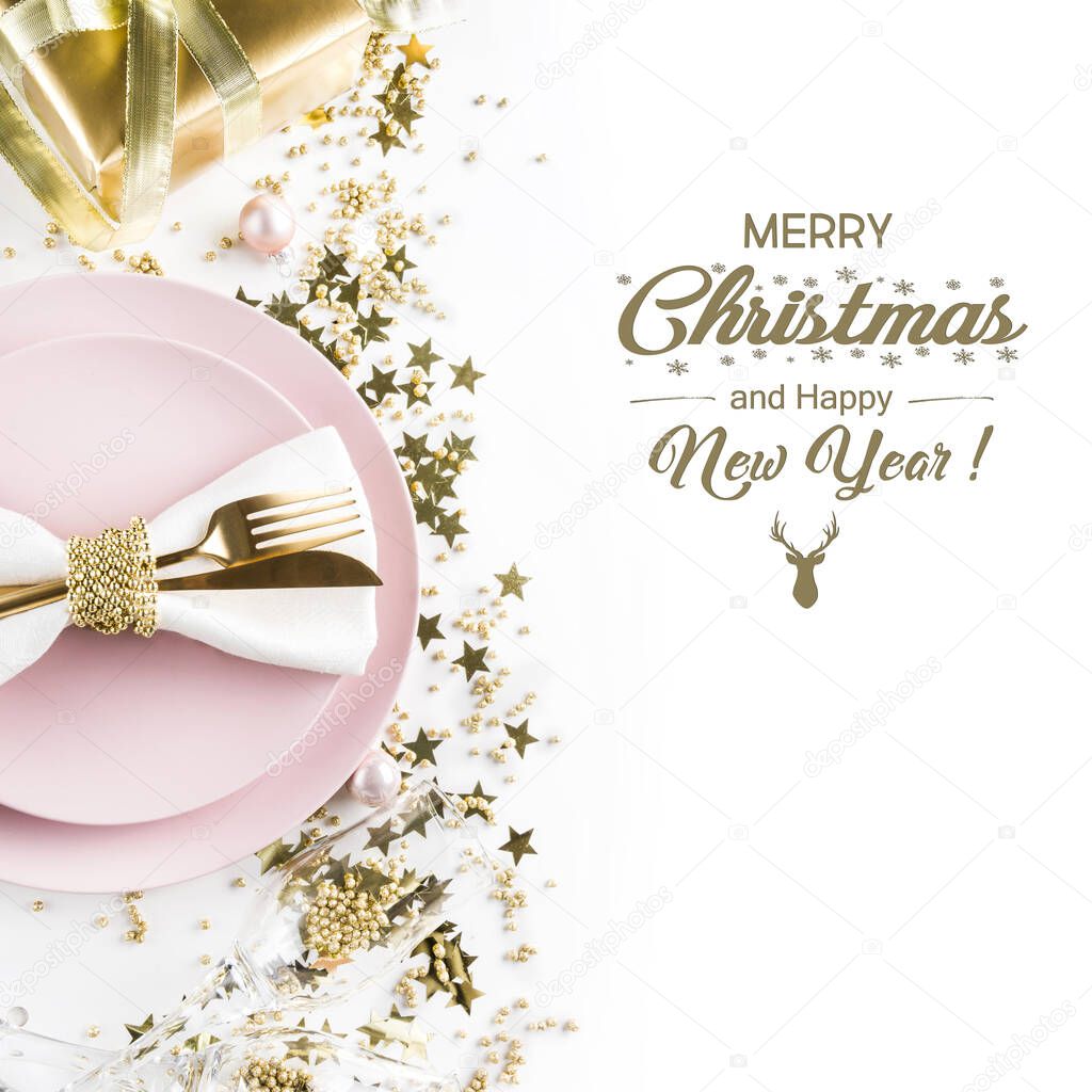 Christmas table setting with pink dishware, golden silverware on white background. Top view.