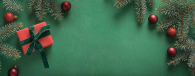 Noel sınırında Noel ağacı ve yeşil arka planda kırmızı hediye. Mutlu noel kartları. Kış tatili - Mutlu yıllar. Metin için boşluk