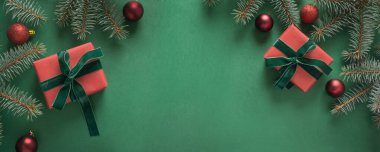 Noel sınırında Noel ağacı ve yeşil perde arkasında kırmızı hediyeler