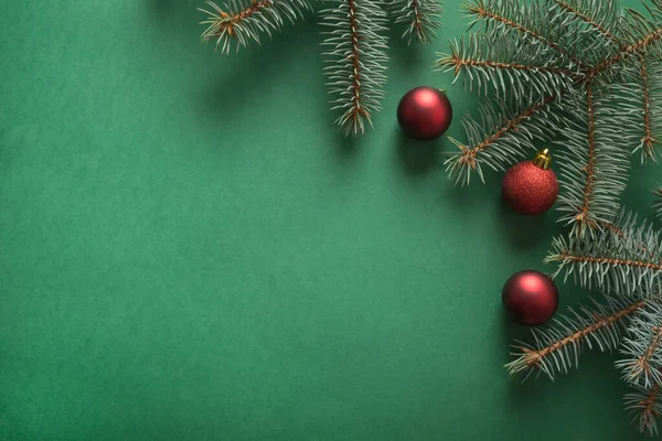 Weihnachtsbaumzweige, rote Glaskugeln auf Grün mit Kopierraum. Ansicht von oben. Urlaubskarte. — Stockfoto