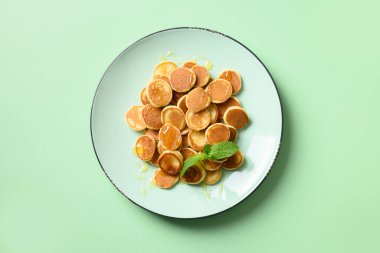 Turkuaz arka planda yeşil tabakta ballı ev yapımı küçük mısır gevreği krepleri. Yukarıdan bak. Lezzetli çocuk kahvaltısı.