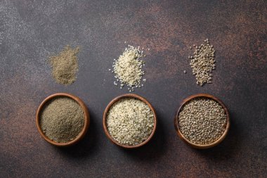 Organik kenevir tohumu, un, kahverengi arka planda üç tahta kasede çekirdekler. Yukarıdan bak. Temiz yemek ve vejetaryen için sağlıklı malzemeler..