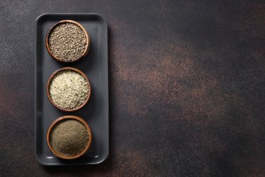 Organik kenevir tohumları, çekirdekler, kahverengi arka plandaki ahşap kaselerde un. Yukarıdan bak. Temiz yemek ve vejetaryen için sağlıklı malzemeler..