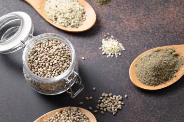 Farklı eyaletlerde kenevir tohumları, çekirdekler, cam kavanozda un ve kahverengi kırsal masada kaşıklar. Faydalı sebze proteini. Kapat..