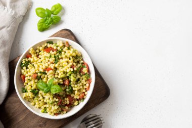 Makarna ve sebzeli ev yapımı salata, domates, beyaz arka planda yeşiller. Üst Manzara. Metin için boşluk.