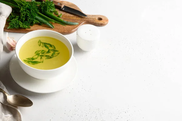 Caldo de pollo con cebolla verde en un tazón blanco sobre una mesa blanca. Copiar espacio. — Foto de Stock