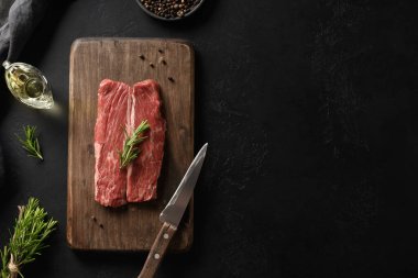 Kesme tahtasında çiğ pirzola ve siyah arka planda biberiye..