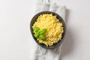 Makarna süslenmiş fesleğen yaprakları siyah kâsede beyaz üzerine. Üst görünüm.
