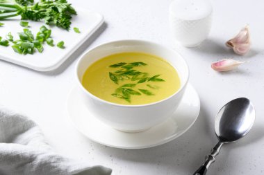 Beyaz masadaki beyaz kasede yeşil soğanlı tavuk çorbası. Boşluğu kopyala.